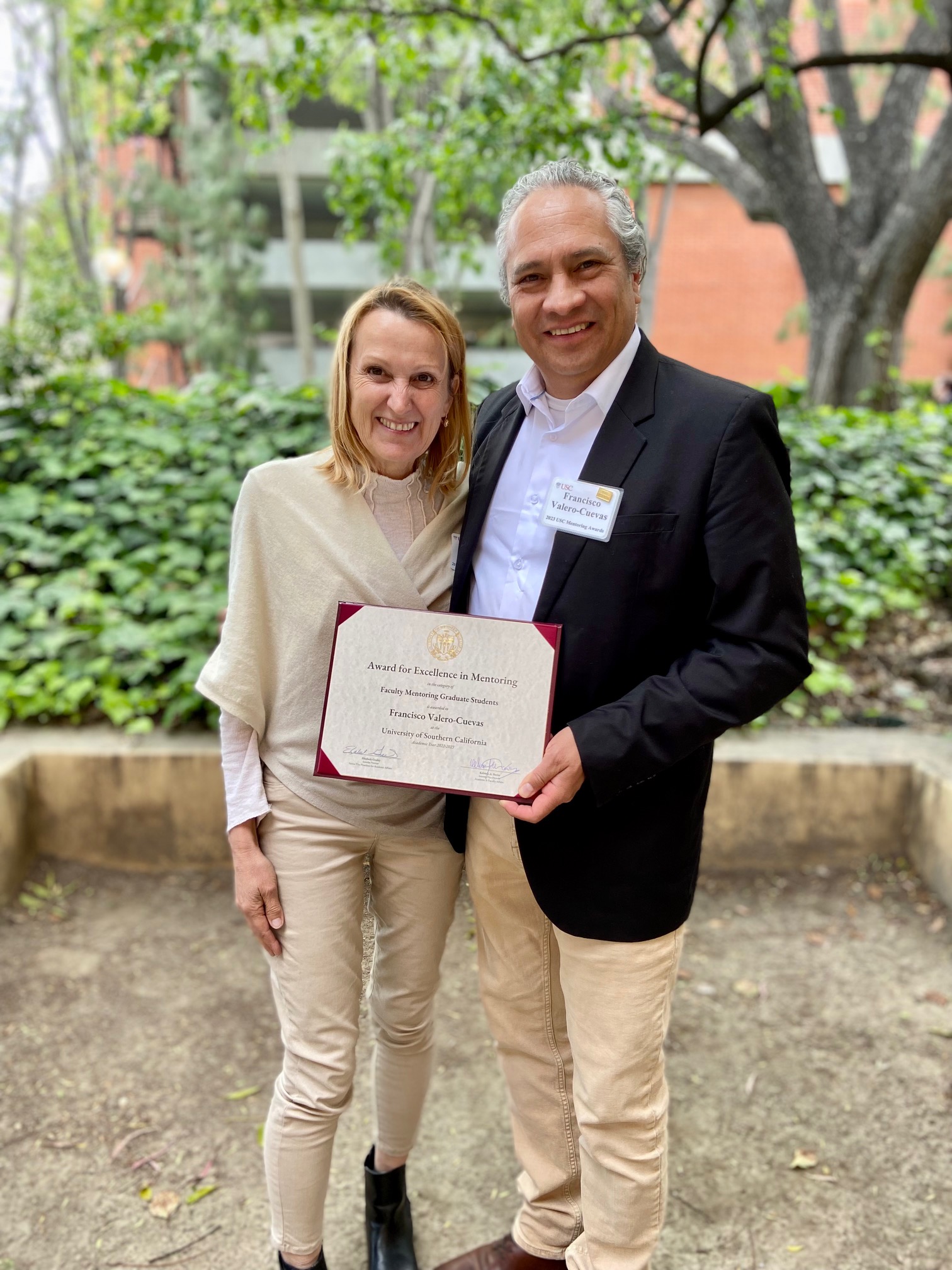 Dr. Francisco Valero-Cuevas (right) smiles for the camera with his wife, Erica (left). Francisco is holding the award he received for Excellence in Mentoring in front of him.